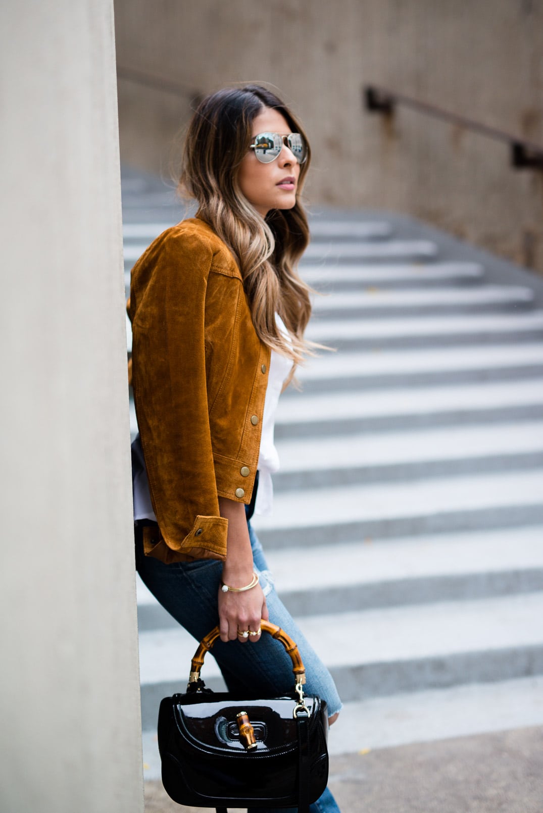 Pam Hetlinger wearing a tan faux suede jacket, nina shoes booties, madewell jeans, white button front shirt, gucci bamboo top handle handbag, free people lace crop top and mirrored aviators