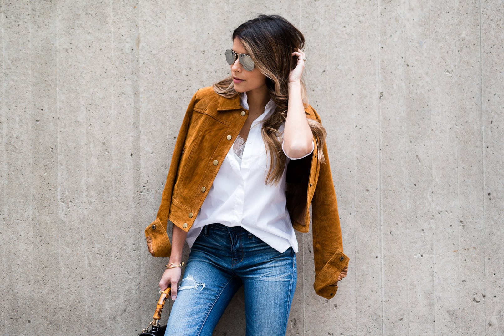 Pam Hetlinger wearing a tan faux suede jacket, nina shoes booties, madewell jeans, white button front shirt, gucci bamboo top handle handbag, free people lace crop top and mirrored aviators