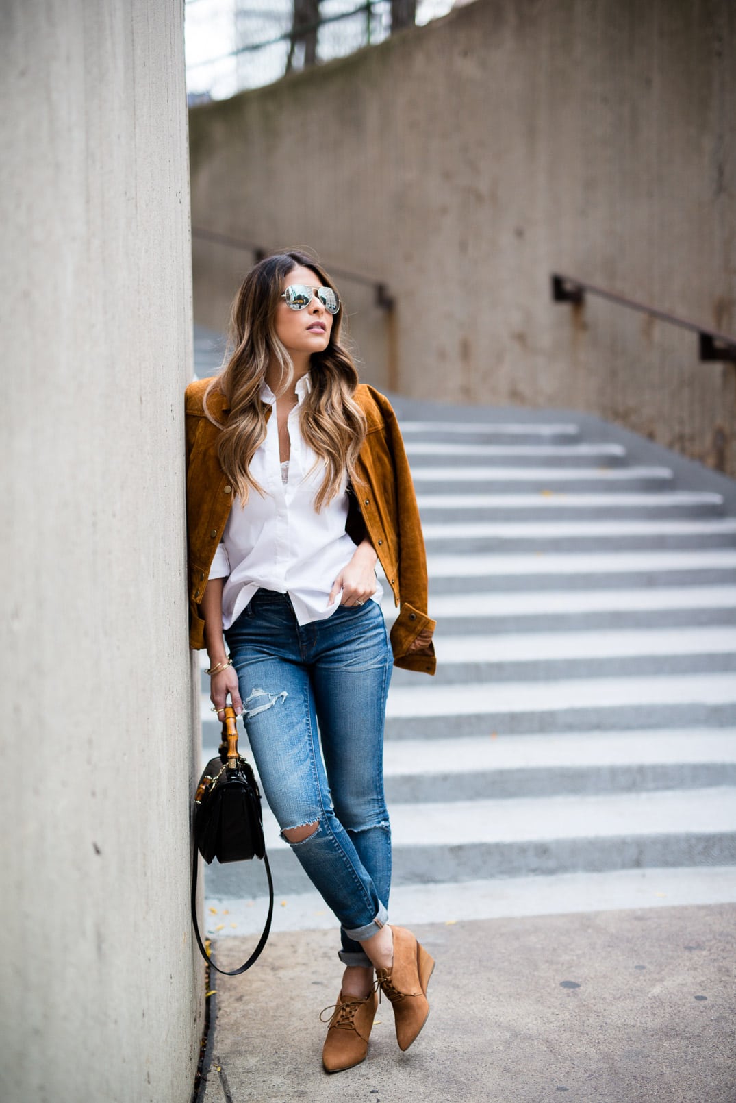 Pam Hetlinger wearing a tan faux suede jacket, nina shoes booties, madewell jeans, white button front shirt, gucci bamboo top handle handbag, free people lace crop top and mirrored aviators