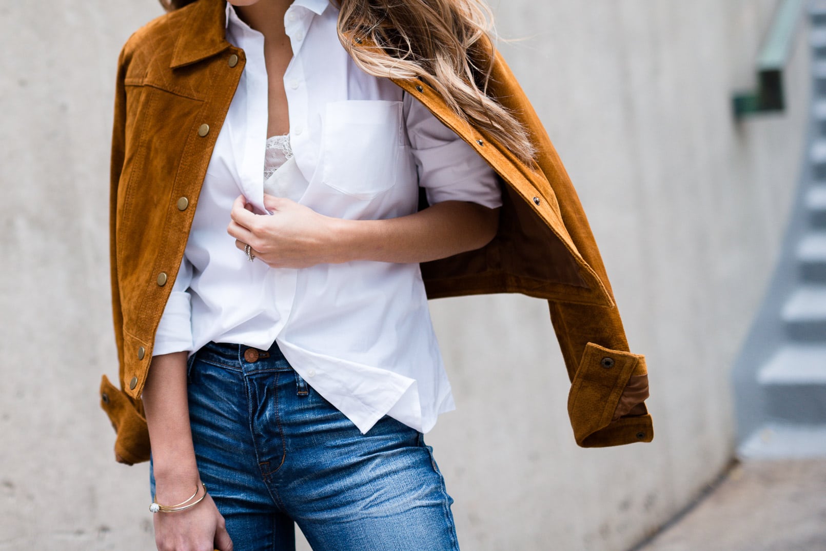 Pam Hetlinger wearing a tan faux suede jacket, nina shoes booties, madewell jeans, white button front shirt, gucci bamboo top handle handbag, free people lace crop top and mirrored aviators