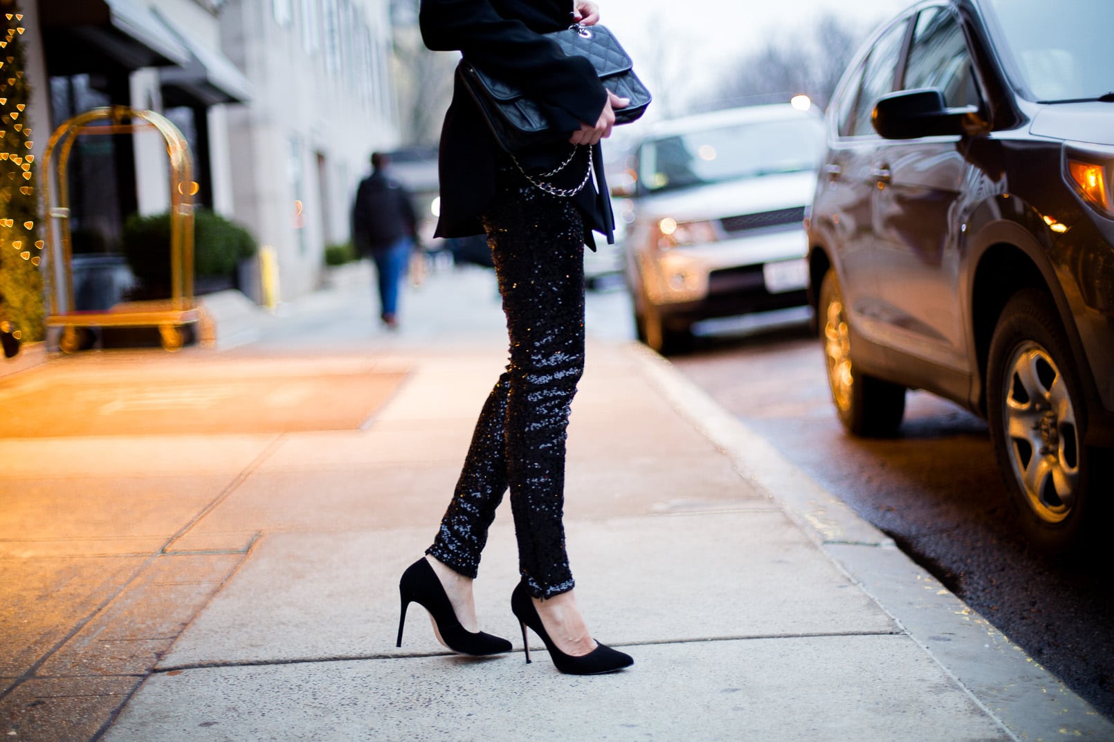 Pam Hetlinger The Girl From Panama wearing H&M sequined pants, zara black belted blazer, black pumps, black wool coat and a chanel bag french riviera flap. holiday look, new years eve look.