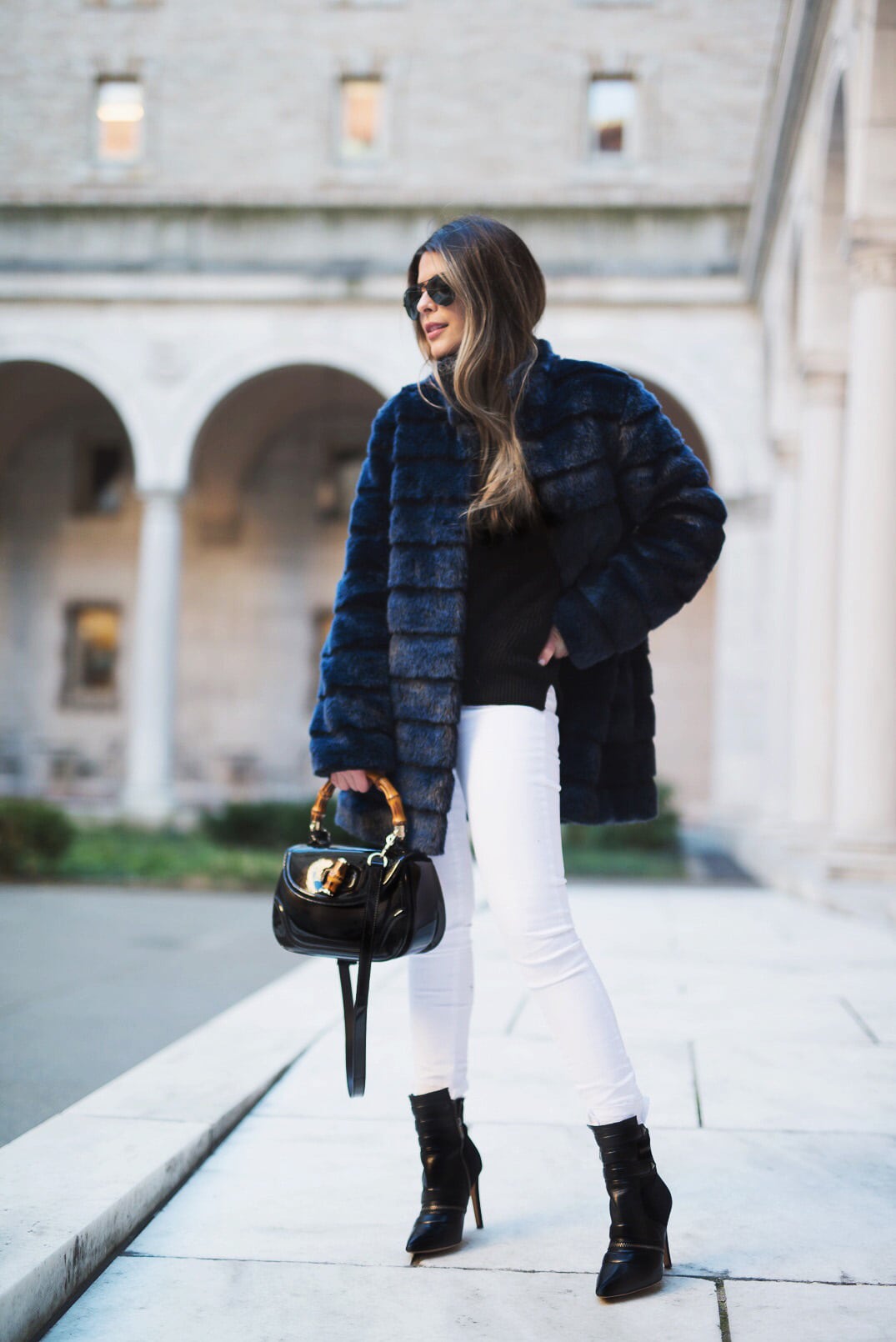 Pam Hetlinger wearing a winter chic outfit, Navy Faux-Fur Coat, White Jeans, Black Booties, Black turtleneck and Gucci Bamboo Bag.