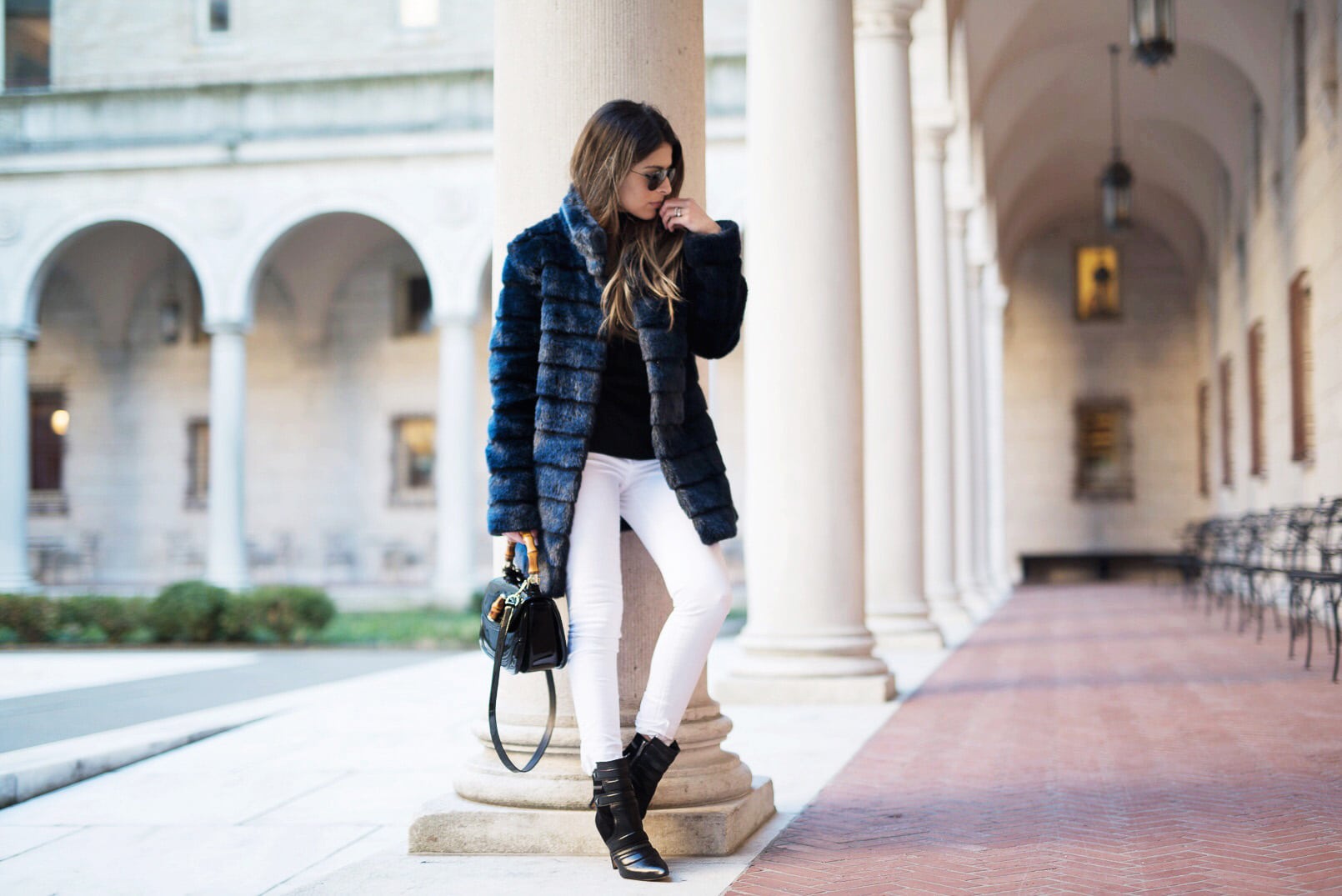 Pam Hetlinger wearing a winter chic outfit, Navy Faux-Fur Coat, White Jeans, Black Booties, Black turtleneck and Gucci Bamboo Bag.