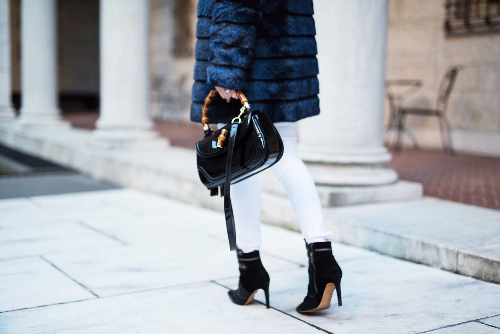 Pam Hetlinger wearing a winter chic outfit, Navy Faux-Fur Coat, White Jeans, Black Booties, Black turtleneck and Gucci Bamboo Bag.