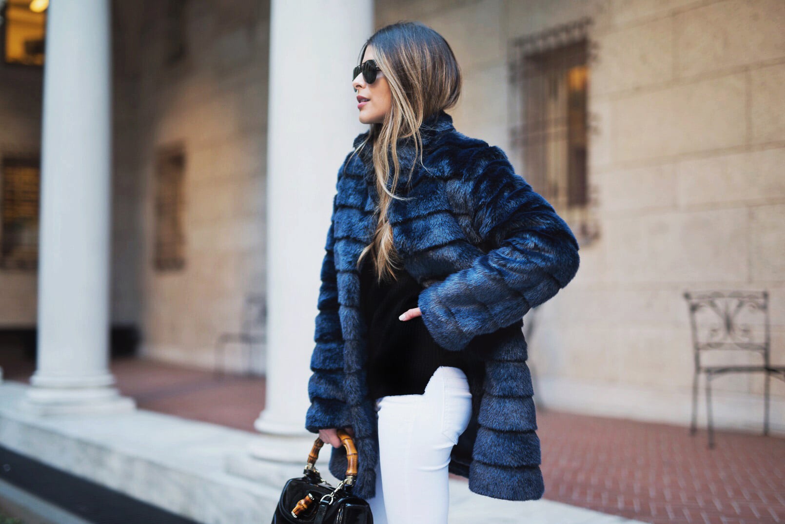 Pam Hetlinger wearing a winter chic outfit, Navy Faux-Fur Coat, White Jeans, Black Booties, Black turtleneck and Gucci Bamboo Bag.