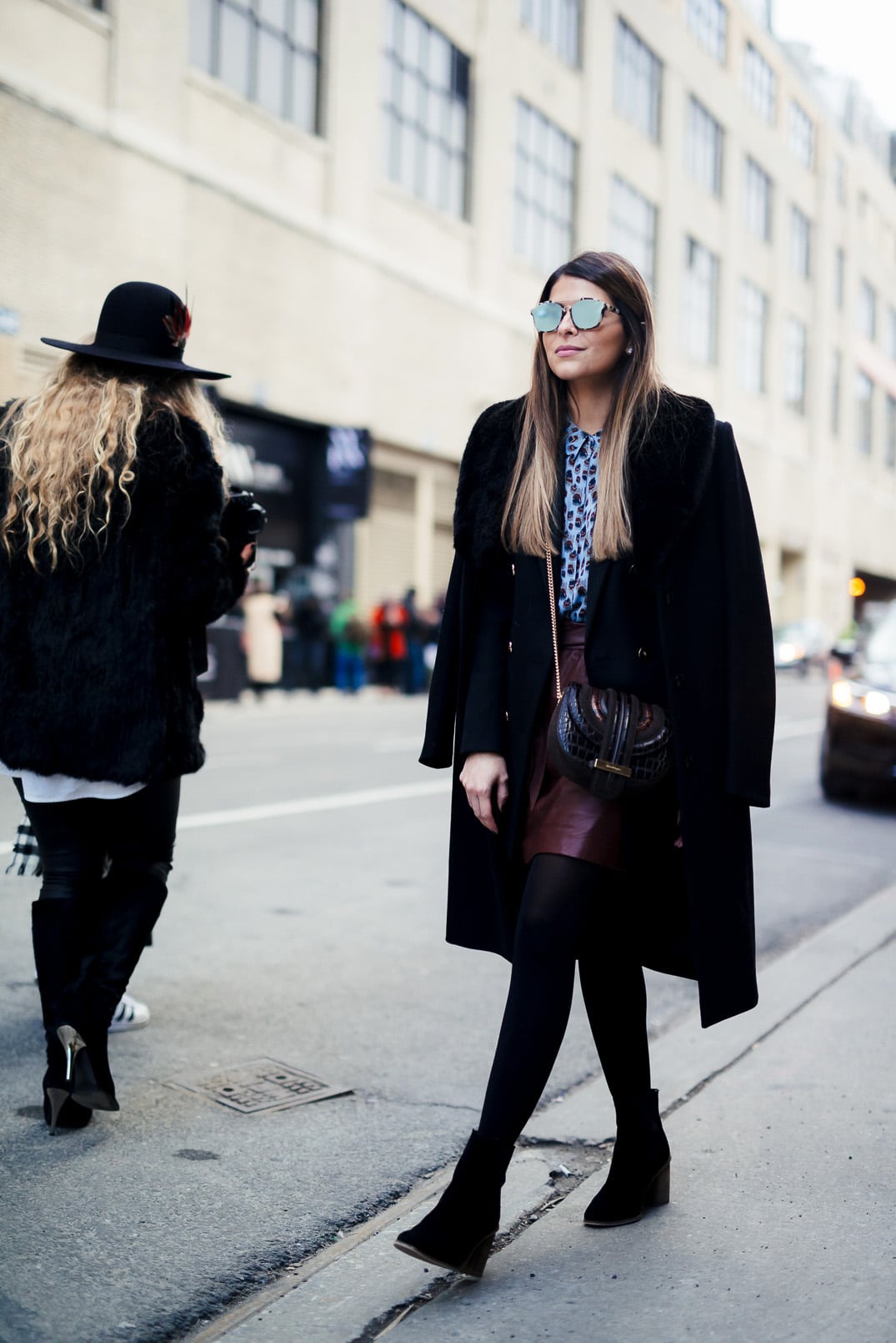 Pam Hetlinger wearing a Reiss printed blouse, black double breasted blazer, black faux fur collar coat, burgundy leather mini skirt and ferragamo bag. New York Fashion Week. 