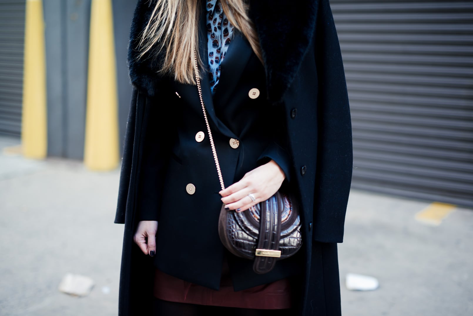 Pam Hetlinger wearing a Reiss printed blouse, black double breasted blazer, black faux fur collar coat, burgundy leather mini skirt and ferragamo bag. New York Fashion Week. 