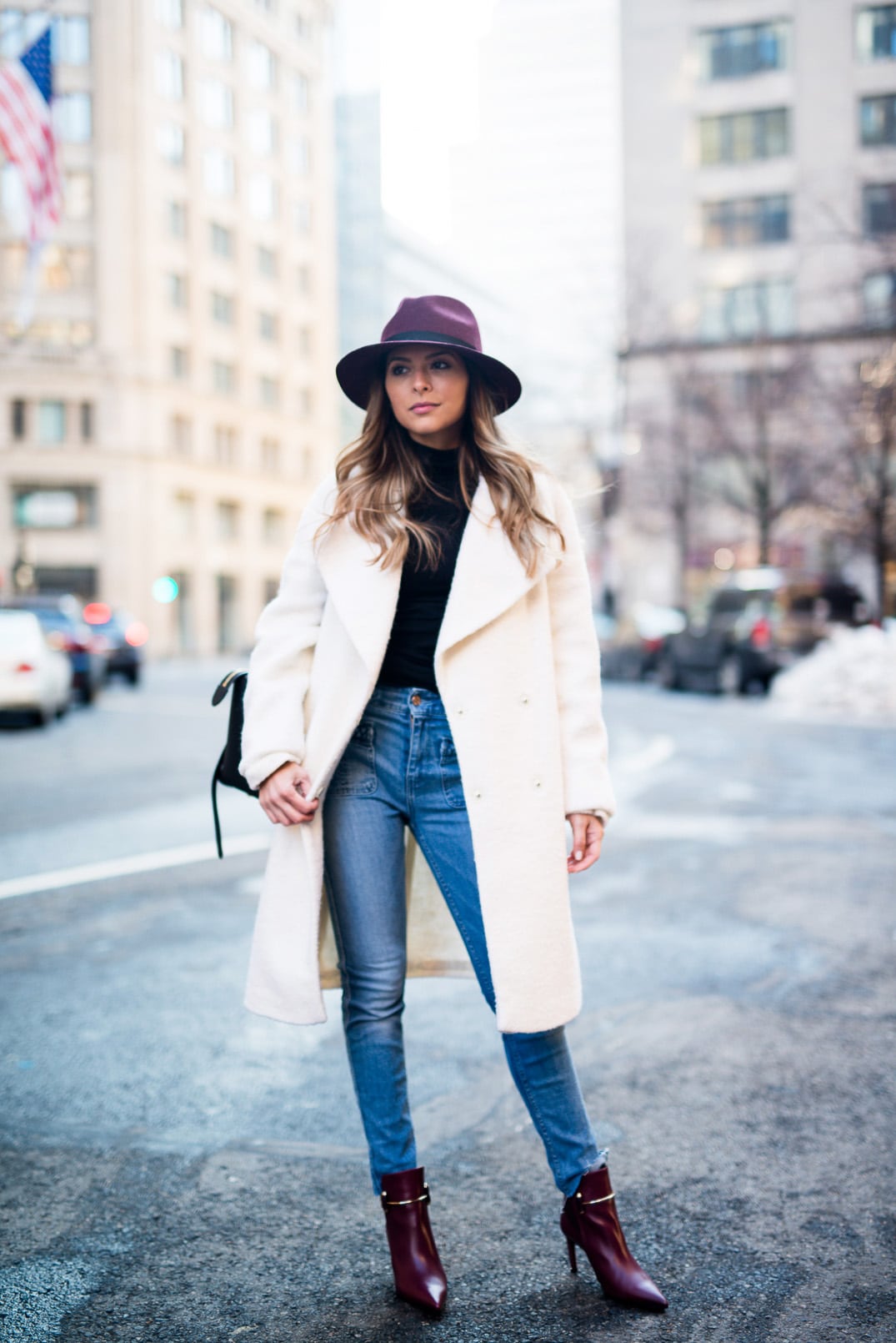 Pam Hetlinger, The Girl From Panama wearing a burgundy hat, asos white oversized coat, 7 for all mankind braided jeans, balenciaga buckle burgundy boots, black turtleneck, How to style a hat in the winter.