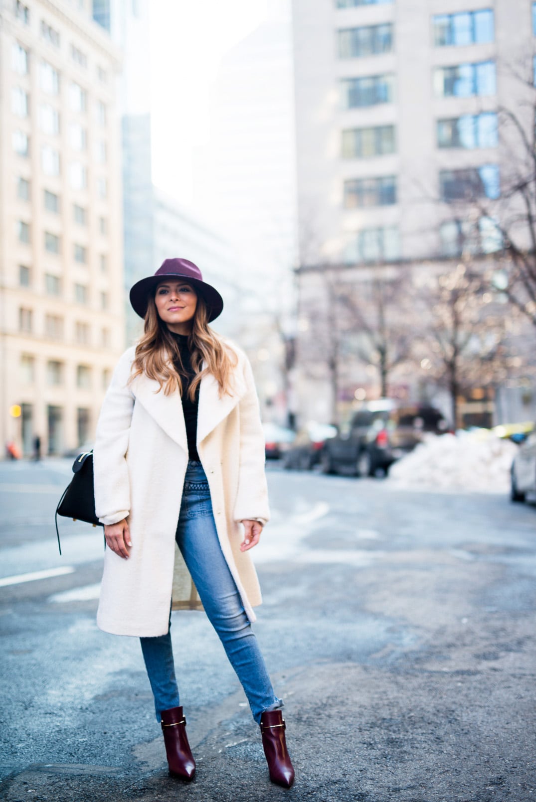 Pam Hetlinger, The Girl From Panama wearing a burgundy hat, asos white oversized coat, 7 for all mankind braided jeans, balenciaga buckle burgundy boots, black turtleneck, How to style a hat in the winter.