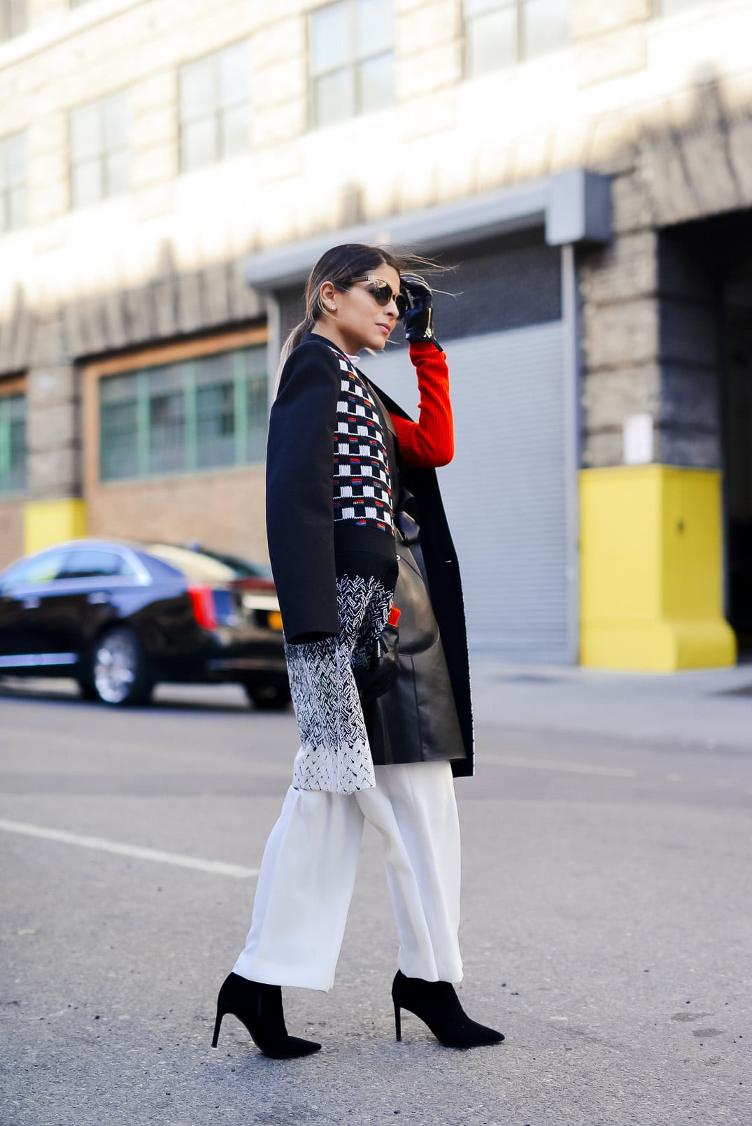 Pam Hetlinger wearing rag and bone red dress, faux-leather vest, white wide leg pants, and black booties