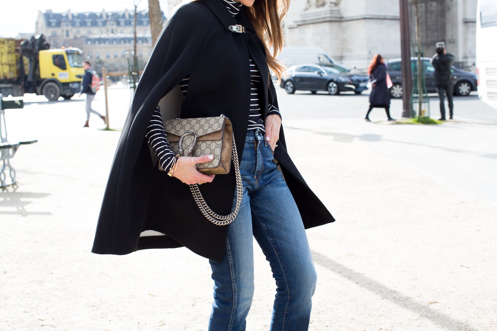 Pam Hetlinger wearing a Kate Spade Jenji Capelet, striped turtleneck, 7 for all Mankind skinny cropped jeans, Gucci Dionysus GG Supreme shoulder bag and balenciage buckle booties. Paris Fashion Week.