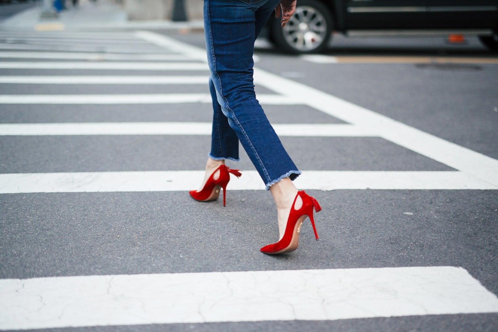 Pam Hetlinger wearing a 7FAM CROPPED HIGH WAIST STRAIGHT WITH RAW HEM, Misha Collection Peplum Top, Gucci Dionysus bag, and Aquazzura Forever Marilyn Pumps in Red.