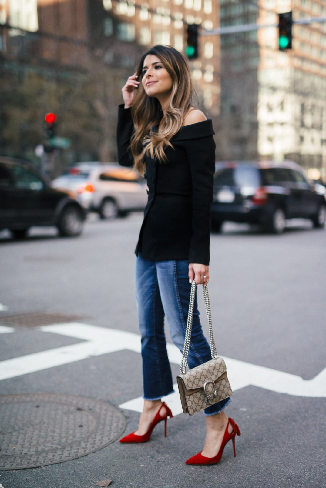 Pam Hetlinger wearing a 7FAM CROPPED HIGH WAIST STRAIGHT WITH RAW HEM, Misha Collection Peplum Top, Gucci Dionysus bag, and Aquazzura Forever Marilyn Pumps in Red.