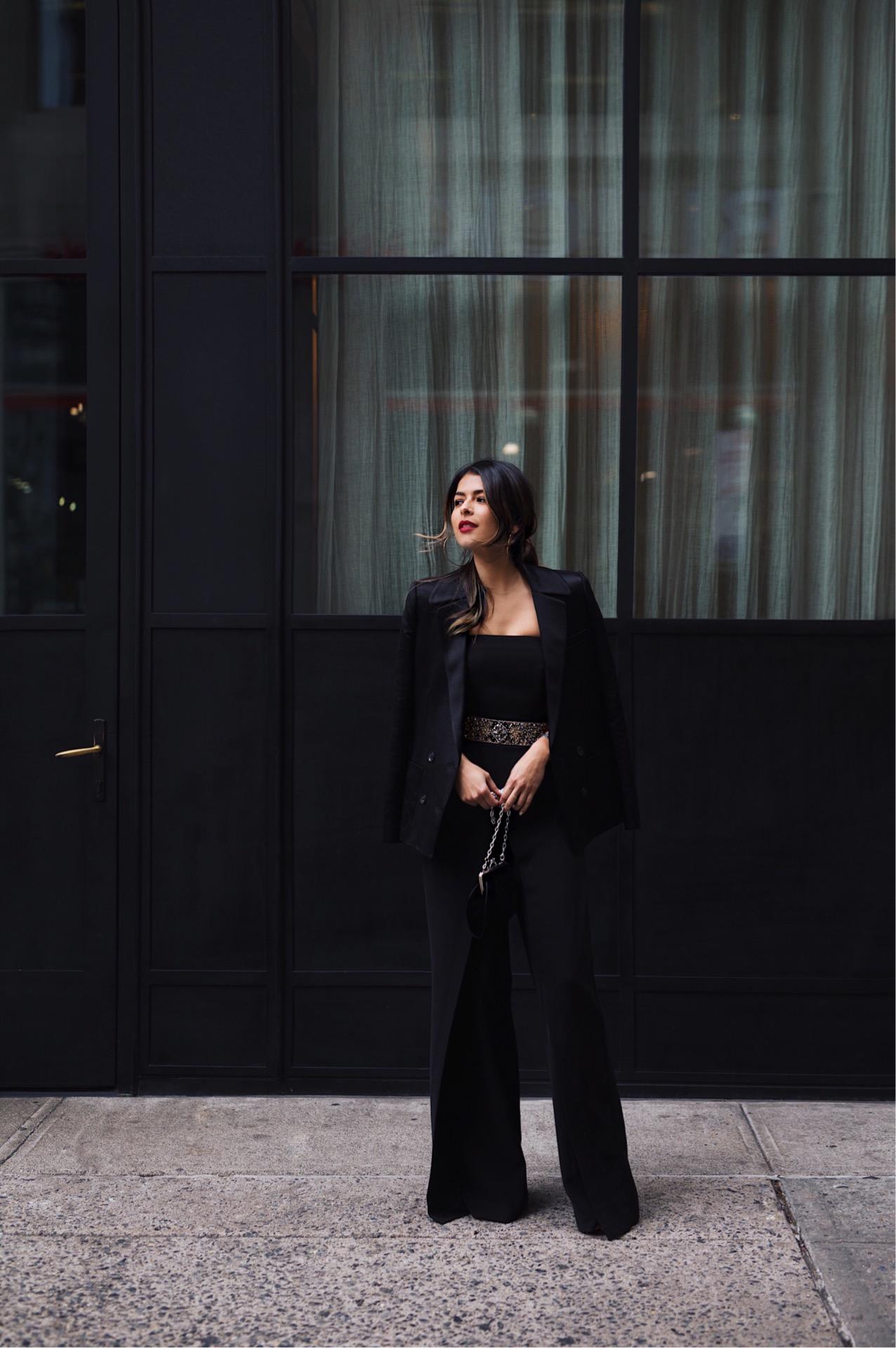 Pam Hetlinger of the fashion, beauty, lifestyle and travel blog The Girl From Panama, wears a White House Black Market jumpsuit and embellished belt, paired with a silk black blazer.