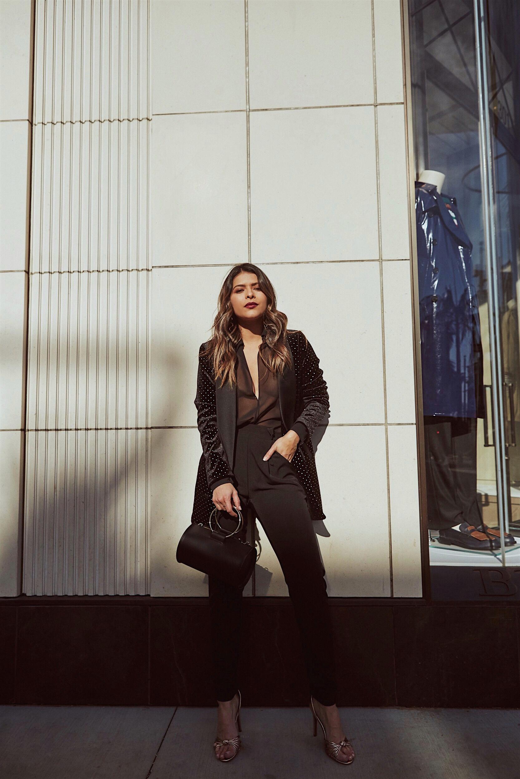 Pam Hetlinger wearing a black velvet blazer and a pant suit with red lip.