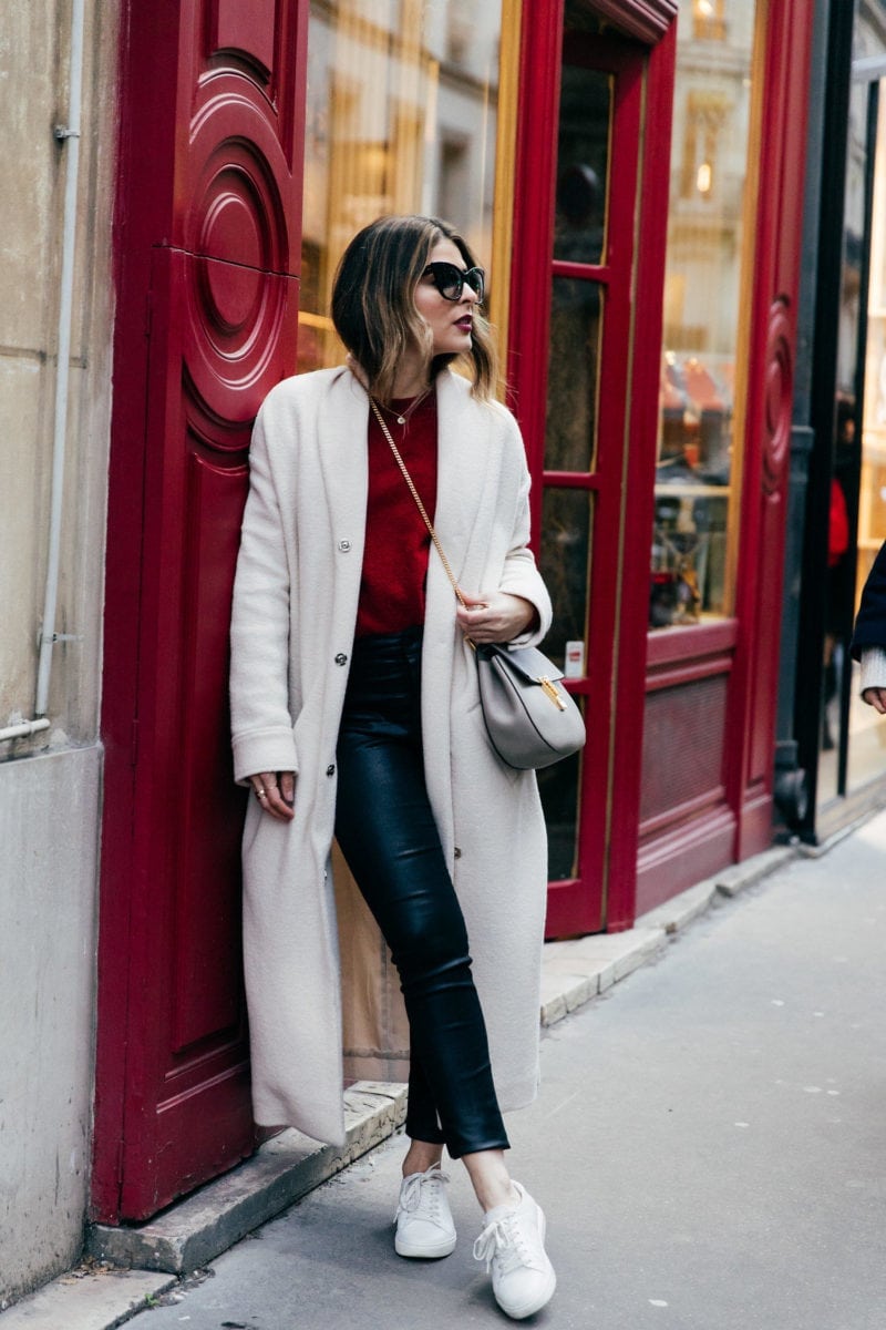 TheGirlFromPanama.com | Paris Travel Guide in the Winter | Pam Hetlinger wearing a red sweater, coated jeans, white sneakers, and a nude coat in Paris France